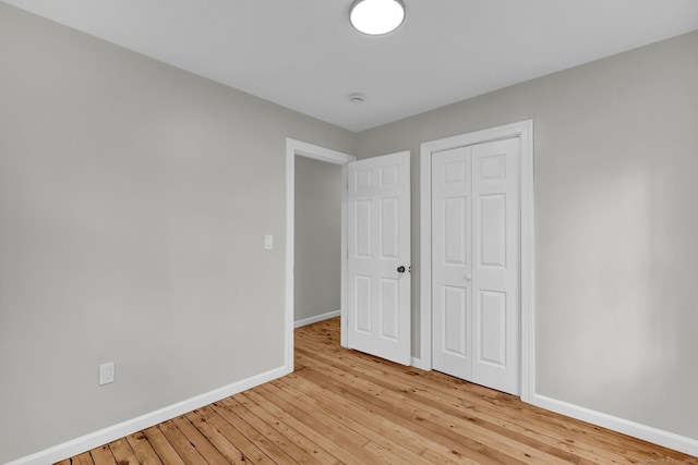 unfurnished bedroom featuring a closet, baseboards, and light wood-style floors