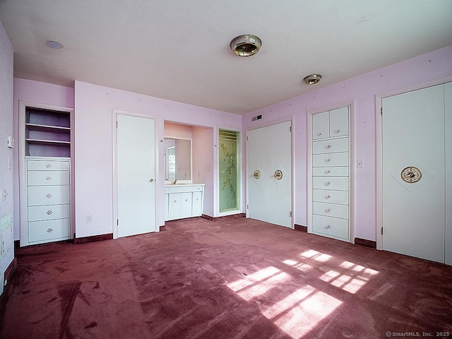unfurnished bedroom featuring carpet floors, multiple closets, and ensuite bathroom