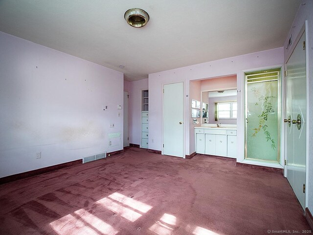 unfurnished bedroom with visible vents, a sink, baseboards, and ensuite bathroom