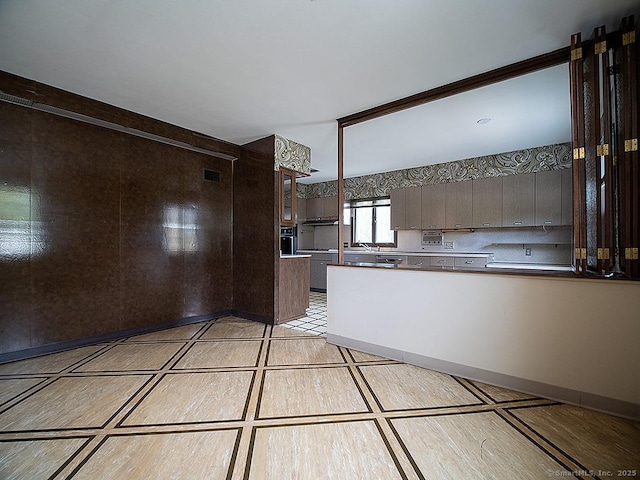kitchen with a sink, dark brown cabinets, a peninsula, and visible vents