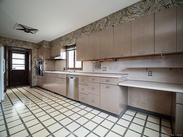 kitchen with light floors, wallpapered walls, light countertops, under cabinet range hood, and appliances with stainless steel finishes