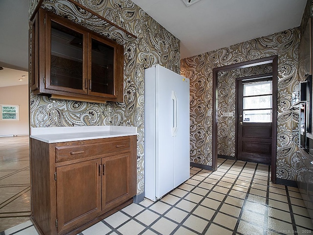 kitchen with light countertops, glass insert cabinets, and wallpapered walls
