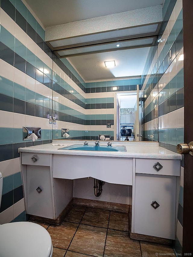 bathroom with toilet, tile patterned floors, tile walls, and vanity