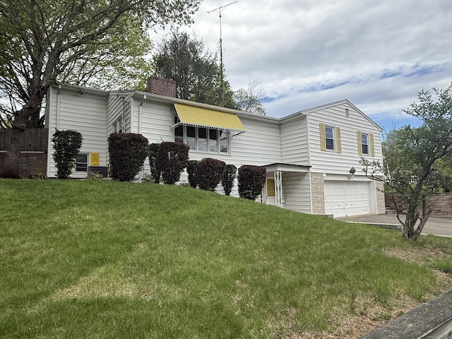 view of side of home featuring a garage, fence, a chimney, and a yard