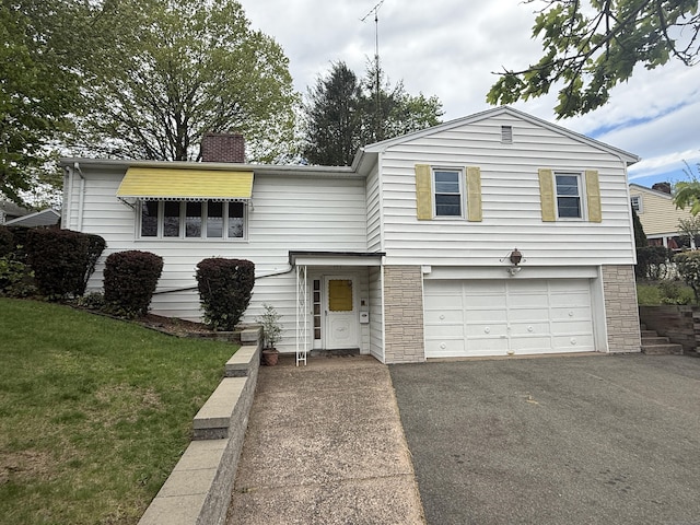 view of front of property with aphalt driveway, a chimney, a front lawn, an attached garage, and stone siding