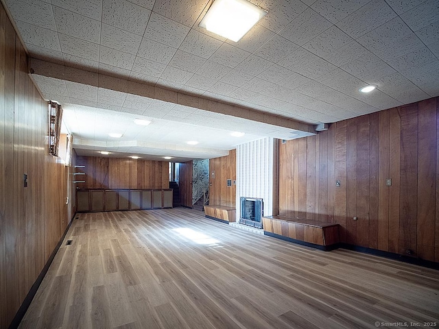 finished below grade area with wooden walls, a fireplace, and wood finished floors