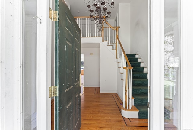 entryway featuring an inviting chandelier, baseboards, stairs, and wood finished floors