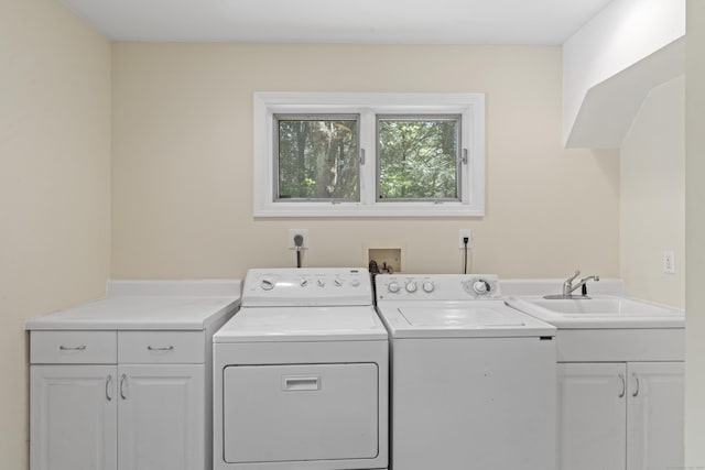 laundry area with separate washer and dryer, a sink, and cabinet space