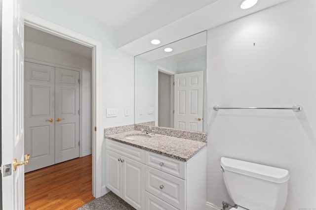 bathroom with recessed lighting, vanity, toilet, and wood finished floors