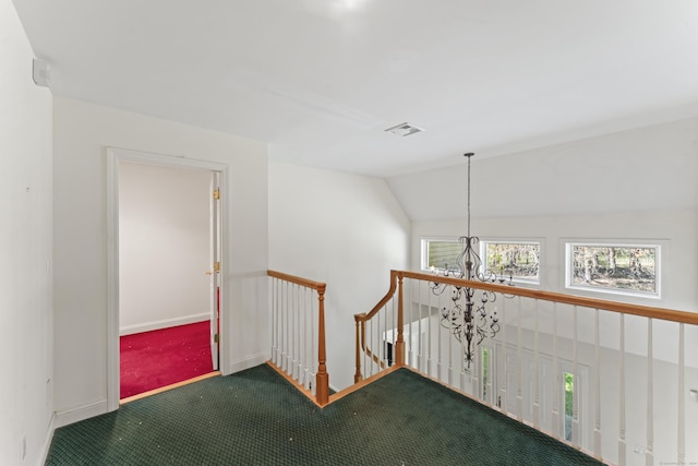 hall featuring plenty of natural light, baseboards, a notable chandelier, and an upstairs landing