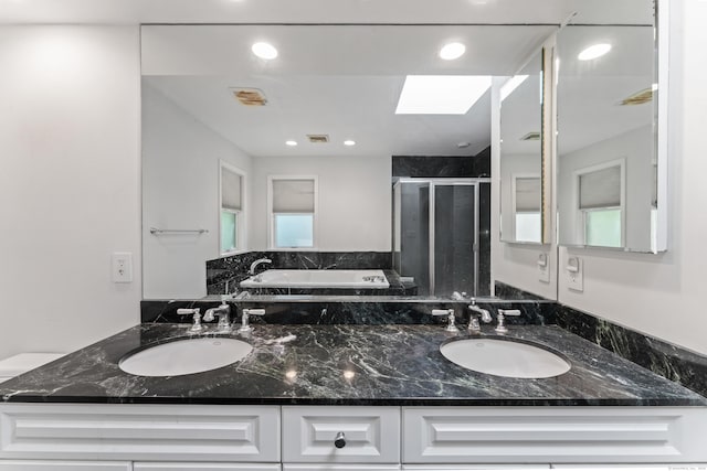 full bath with a sink, a skylight, a shower stall, and a garden tub