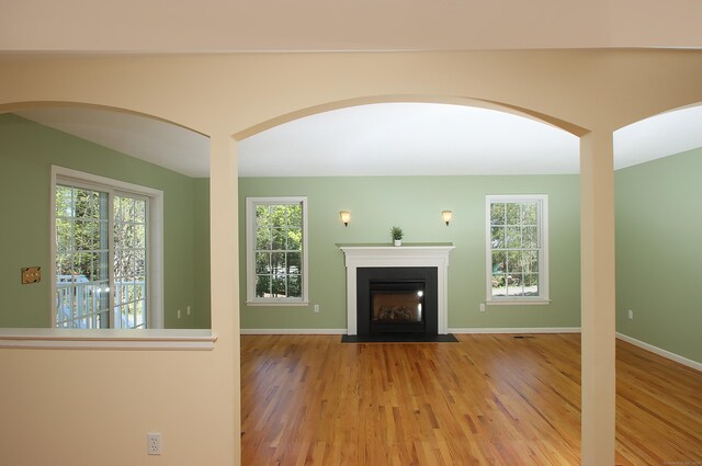 unfurnished living room with baseboards, a fireplace with flush hearth, and wood finished floors