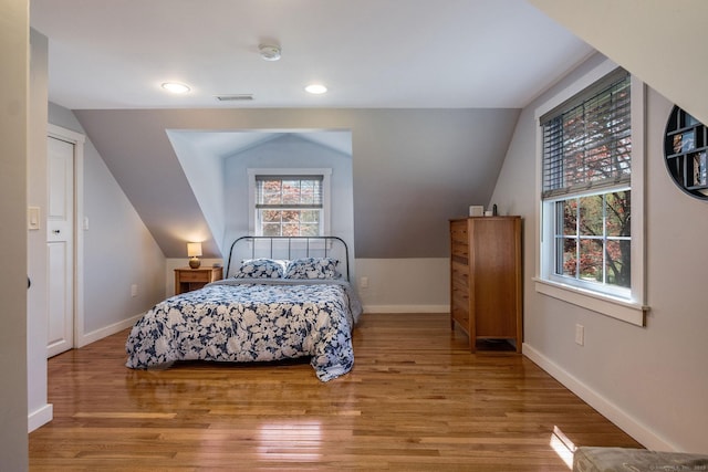 bedroom featuring visible vents, lofted ceiling, wood finished floors, baseboards, and recessed lighting