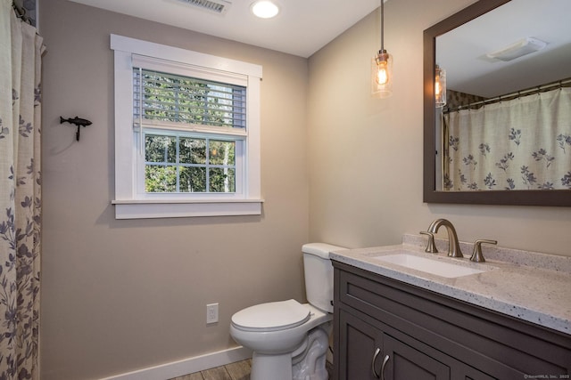 bathroom featuring visible vents, vanity, wood finished floors, toilet, and baseboards