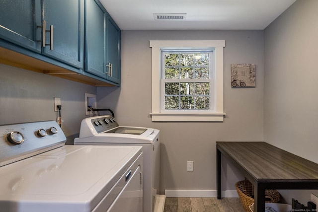 clothes washing area featuring cabinet space, light wood-style flooring, baseboards, visible vents, and washer and clothes dryer