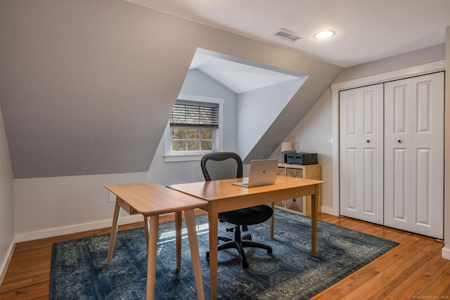 home office with vaulted ceiling, light wood finished floors, and visible vents