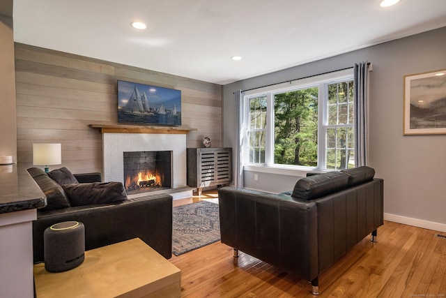 living area featuring baseboards, recessed lighting, light wood-style flooring, and a fireplace