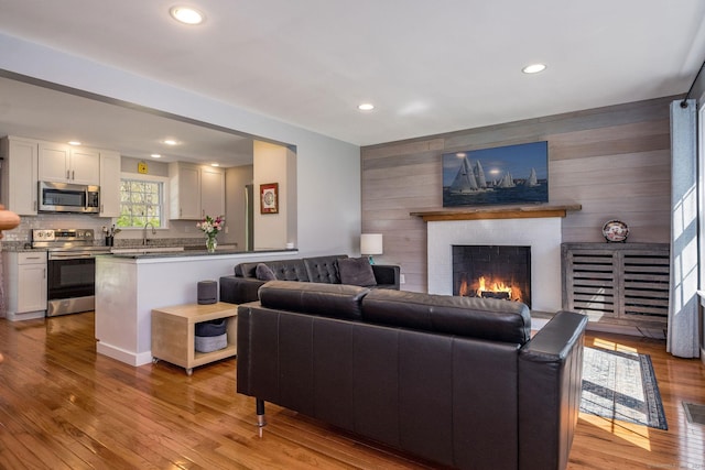 living room with wooden walls, light wood-style flooring, and a fireplace