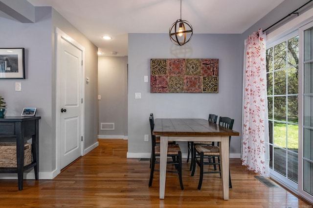 dining area with baseboards, visible vents, and wood finished floors