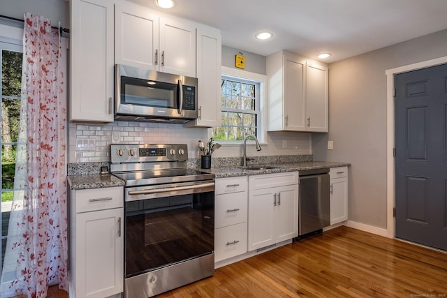 kitchen with stainless steel appliances, light wood-type flooring, a sink, and tasteful backsplash