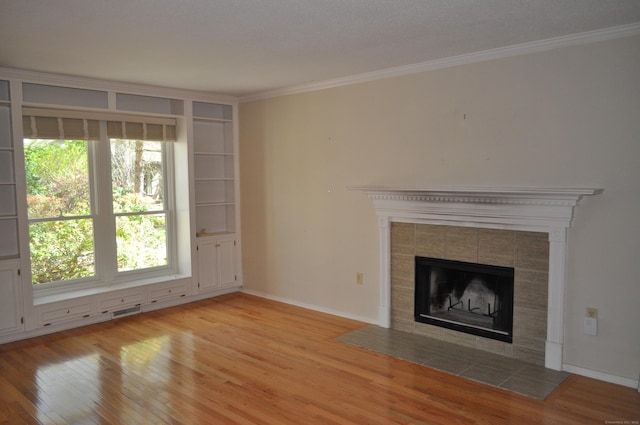 unfurnished living room featuring light wood-style flooring, baseboards, a tile fireplace, visible vents, and ornamental molding