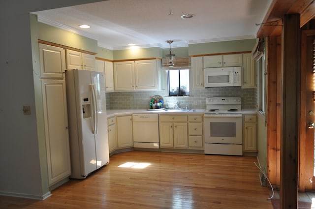 kitchen with a sink, light countertops, ornamental molding, and white appliances