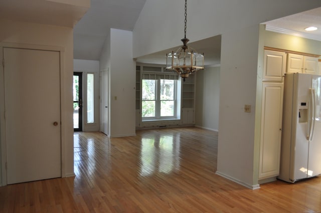 unfurnished dining area with baseboards, an inviting chandelier, ornamental molding, and light wood-type flooring