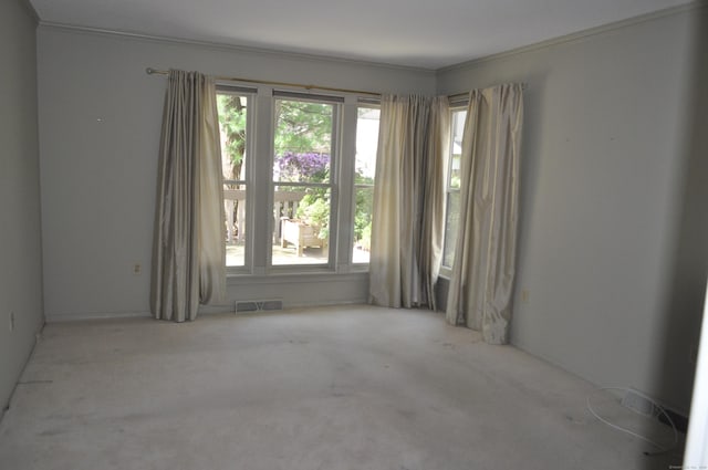 carpeted spare room featuring crown molding and visible vents