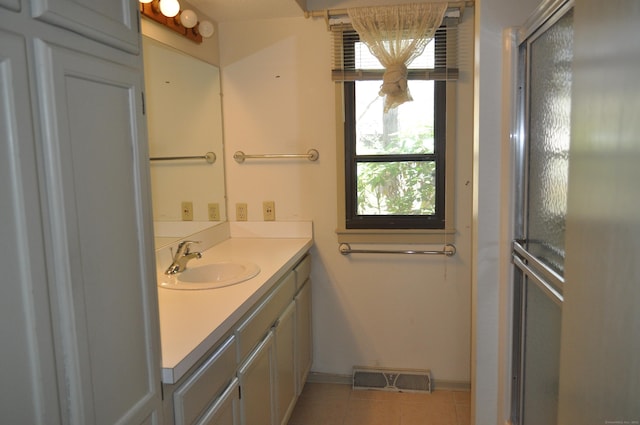 bathroom featuring tile patterned flooring, visible vents, vanity, a healthy amount of sunlight, and baseboards