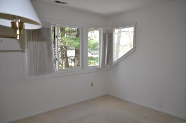 spare room featuring carpet flooring, baseboards, and visible vents