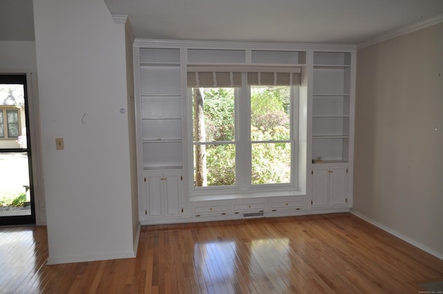 empty room featuring plenty of natural light, ornamental molding, light wood finished floors, and visible vents