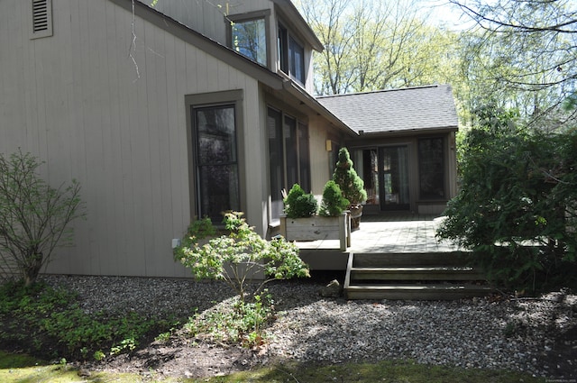 view of home's exterior with a shingled roof and a deck