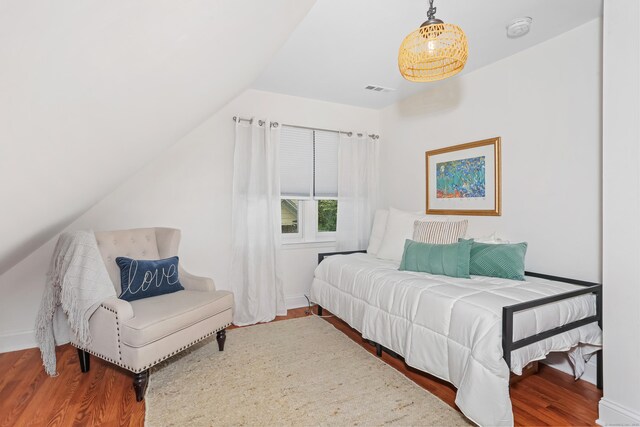 bedroom featuring wood finished floors, vaulted ceiling, and baseboards