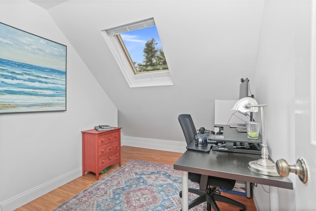 office space with a skylight, light wood-style floors, baseboards, and vaulted ceiling