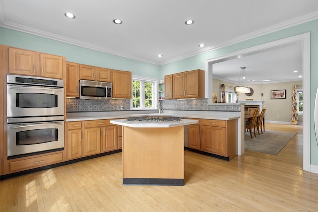 kitchen featuring tasteful backsplash, light wood-style flooring, light countertops, a kitchen island, and appliances with stainless steel finishes