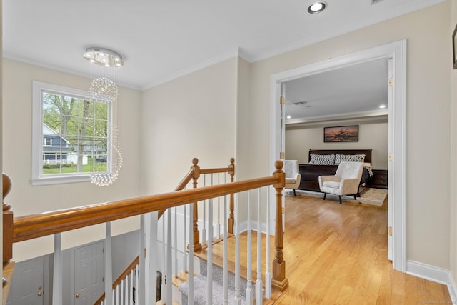 hall featuring light wood finished floors, an upstairs landing, ornamental molding, and recessed lighting