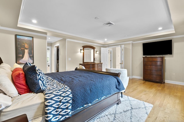 bedroom featuring a tray ceiling, ornamental molding, visible vents, and light wood-style floors