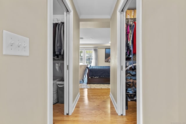 corridor featuring light wood finished floors, baseboards, and ornamental molding