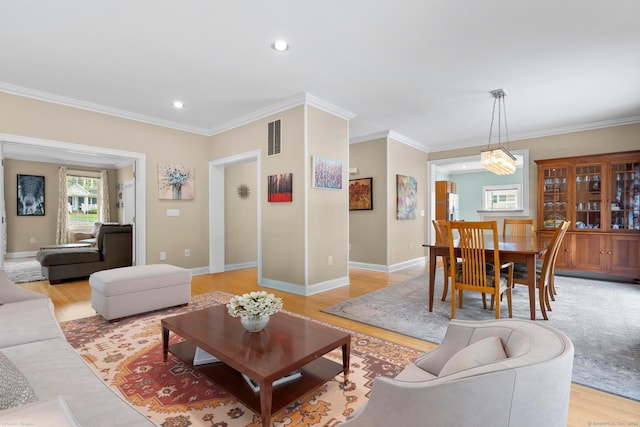 living room with ornamental molding, baseboards, light wood-style flooring, and visible vents