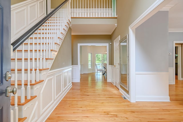 127 Hanover Rd, Newtown, CT 06470 - foyer with crown molding, light wood-type flooring, stairway, wainscoting, and a decorative wall