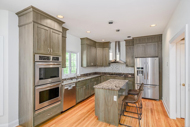 127 Hanover Rd, Newtown, CT 06470 - kitchen with appliances with stainless steel finishes, wall chimney range hood, dark stone counters, light wood-type flooring, and a sink