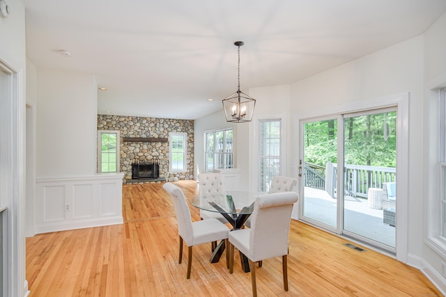 127 Hanover Rd, Newtown, CT 06470 - dining area with light wood finished floors, a stone fireplace, and a chandelier