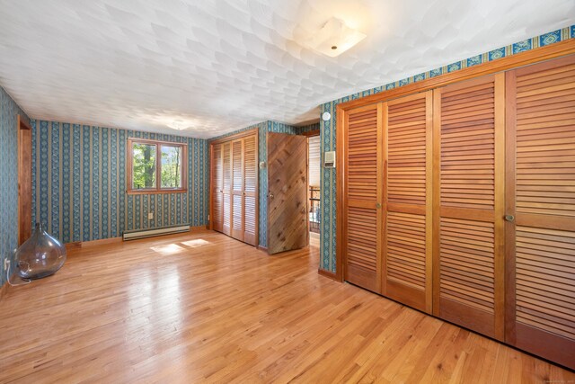 161 Center Hill Rd, Barkhamsted, CT 06063 - unfurnished bedroom with a baseboard radiator, wallpapered walls, wood finished floors, and two closets
