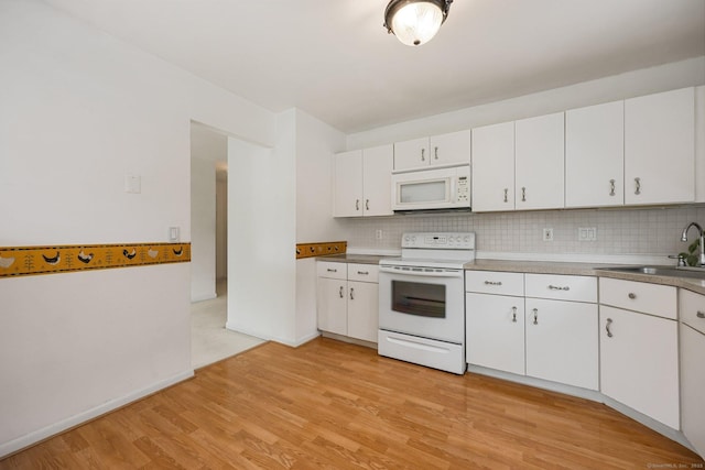 97 Richards Ave Apt F5, Norwalk, CT 06854 - kitchen with white cabinets, a sink, light wood finished floors, white appliances, and tasteful backsplash
