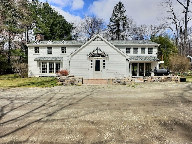 traditional home featuring a chimney and roof with shingles