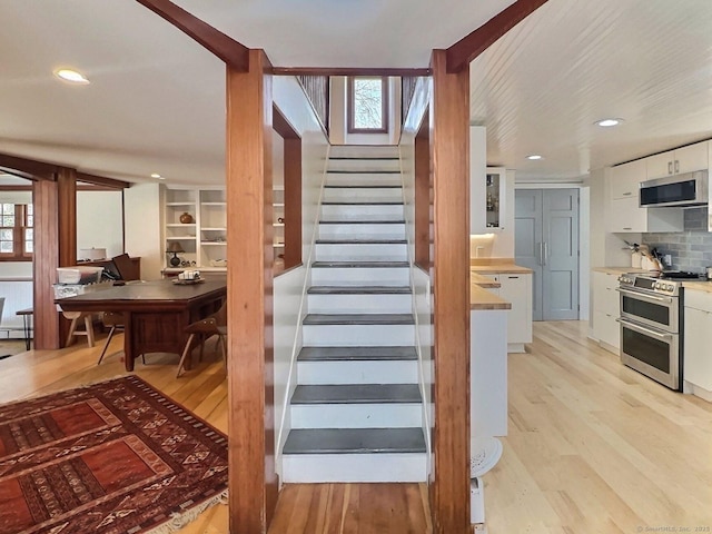 stairs with wood finished floors and recessed lighting