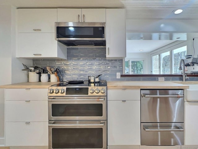 kitchen featuring appliances with stainless steel finishes, light countertops, decorative backsplash, and white cabinets