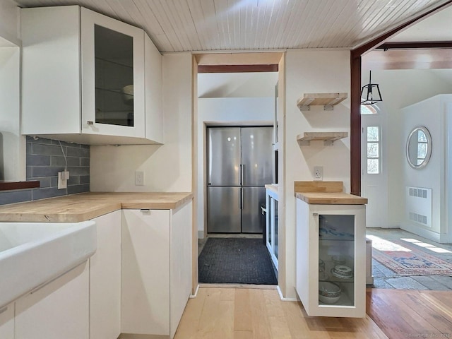 kitchen with white cabinetry, light wood-style floors, decorative backsplash, glass insert cabinets, and high quality fridge