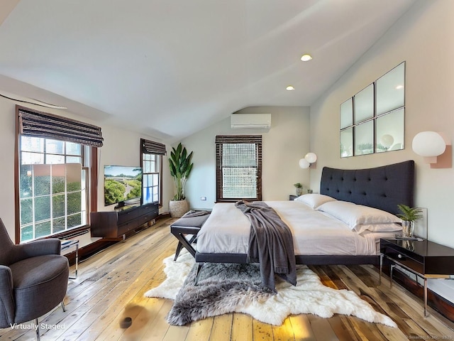 bedroom with light wood-style flooring, vaulted ceiling, an AC wall unit, and recessed lighting