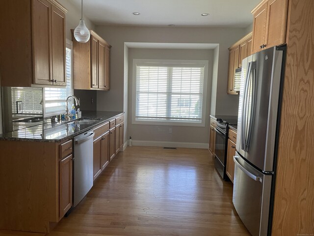 kitchen featuring wood finished floors, baseboards, a sink, a wealth of natural light, and stainless steel appliances